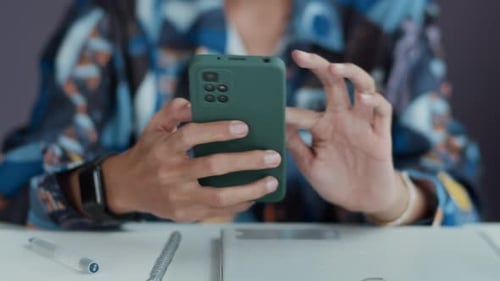 Person Using a Smartphone Indoors at Desk