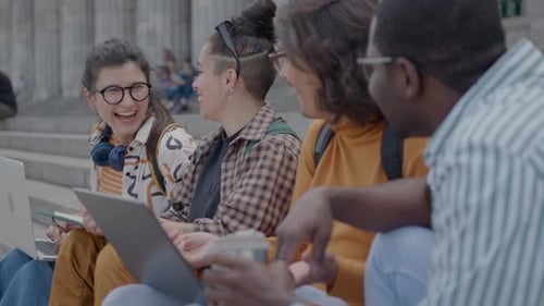 Joyful Female Student Chatting with Friends on Stairs Outside University