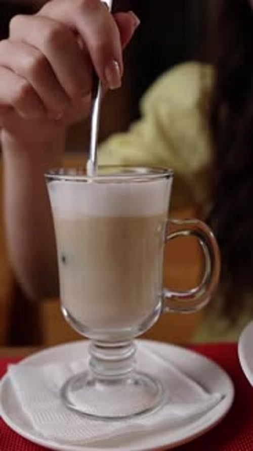 A girl drinking delicious coffee with milk in a cafe