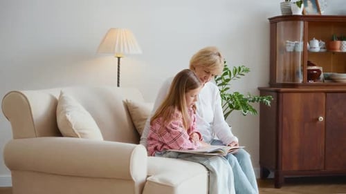 Child Reading Book with Adult on Couch