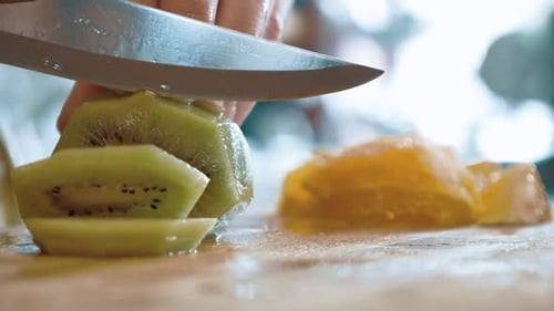 Kiwi Fruit Being Sliced on Cutting Board