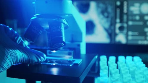 Gloved Hand Preparing Microscope in Lab