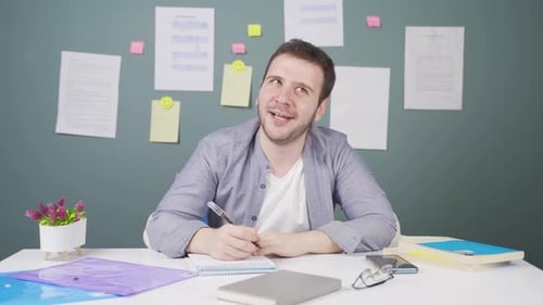 Young Man Writing at Desk with Papers