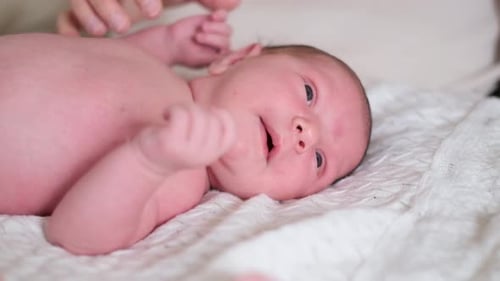 Peaceful Infant Lying on Soft White Blanket
