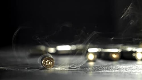 Smoking bullet casings on dark surface in close up