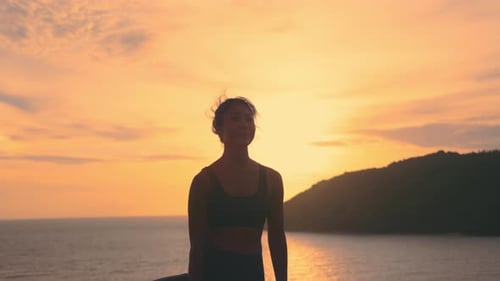 Woman Practices Yoga at the Ocean During Sunset