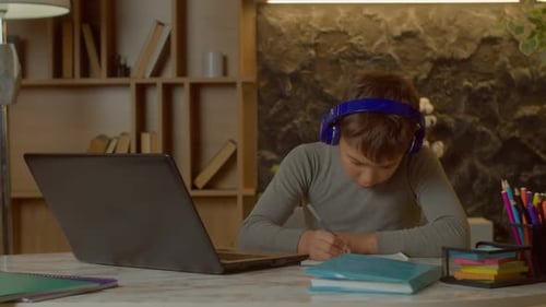 Boy Studying with Laptop and Headphones at Home