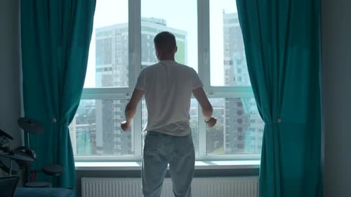 Man Stretching Arms in Apartment Window at Daytime