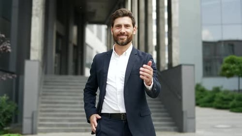 Smiling Businessman Offers Handshake in Front of Office