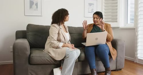 Ouverture d'un ordinateur portable argenté, collègues féminines discutant du projet, posant des questions et clarifiant sur le canapé