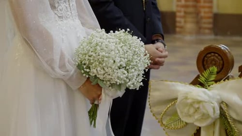 The bride and groom are standing next to each other in the church, with the bride holding a wedding