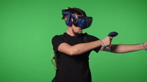 A Man Uses Virtual Reality Glasses to Play in a Studio on a Green Background