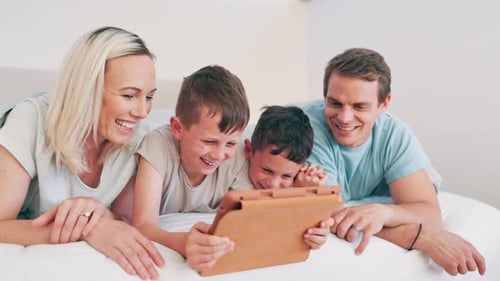 Family Laughing Together in Bed with Tablet