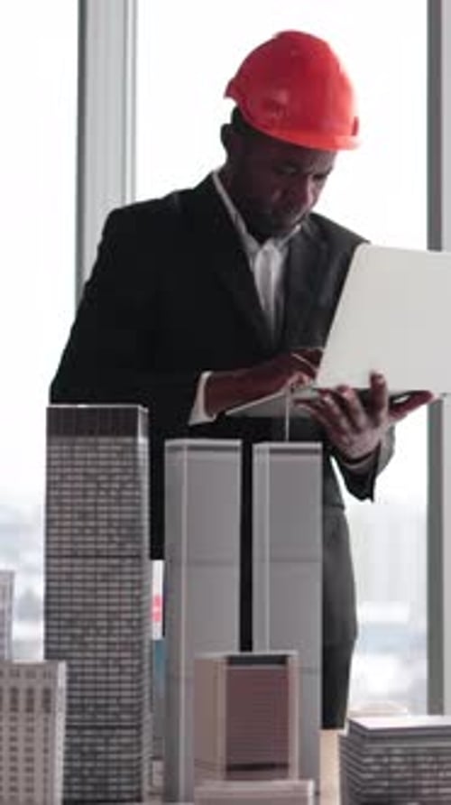 Architect Examines Building Models While Using Laptop