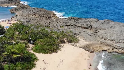 Aerial footage of a rock formation in a beach.