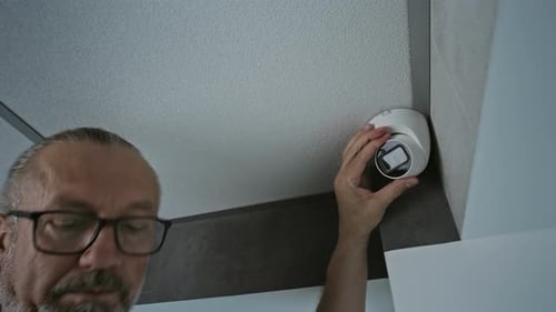 Man Installs Security Camera Checking Settings On Tablet