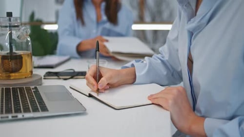 Writing in notebook at bright office desk