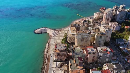 Aerial drone view of the Durres coastline showing tall apartment buildings, turquoise sea, and the u