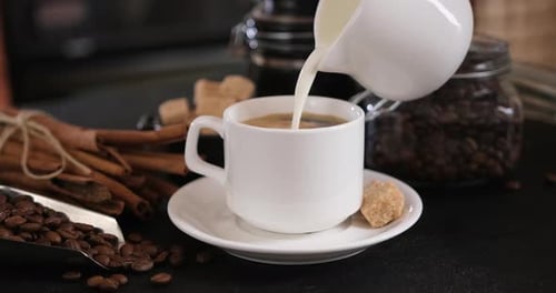Pouring Milk into Coffee Cup on Table