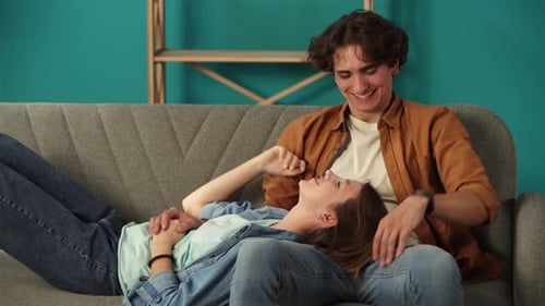 Close Up of Living Room Man Sitting on the Sofa in New Apartment Woman Laying on His Thighs Happy