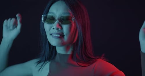 Slow Motion of Carefree Asian Woman Dancing in Neon Light on Dark Background