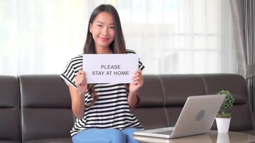 Smiling Woman Holding a Stay at Home Sign