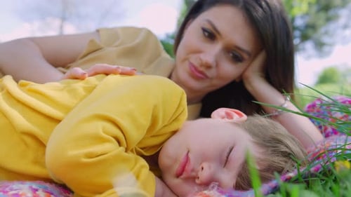 Woman Watches Over Sleeping Child in a Park