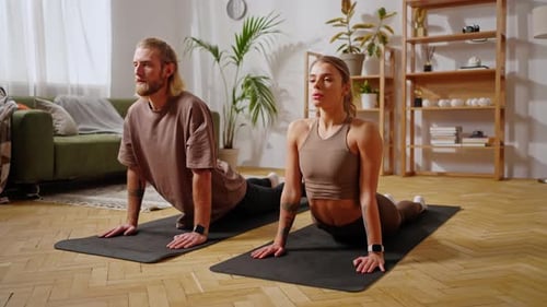 Pareja acostada en colchonetas y haciendo yoga para relajarse en casa