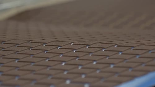 lots of brown, square, chocolate-flavored cookies on the conveyor line