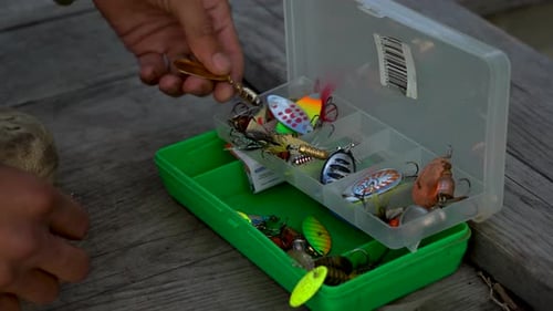 Der Fischer wechselt das Angelgerät. Box für Haken, Köder und Wobbler