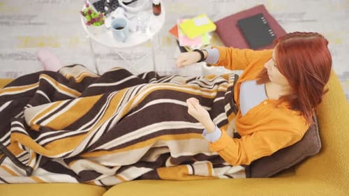 Woman Lying on Couch Taking Pill