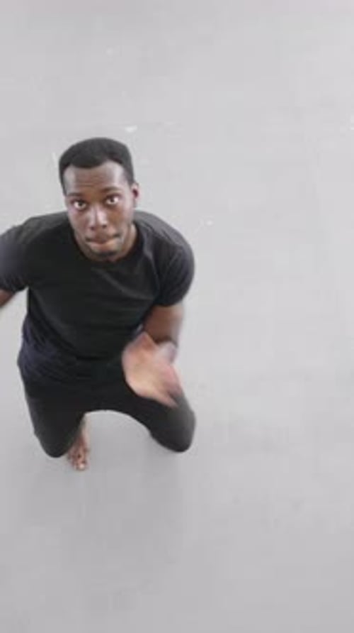 Homme afro-américain dansant énergiquement sur un sol lisse dans un espace ouvert lumineux