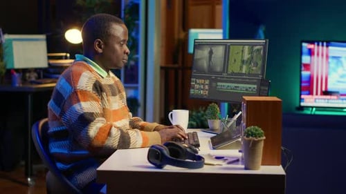 Adult Edits Video at Computer in Dark Office