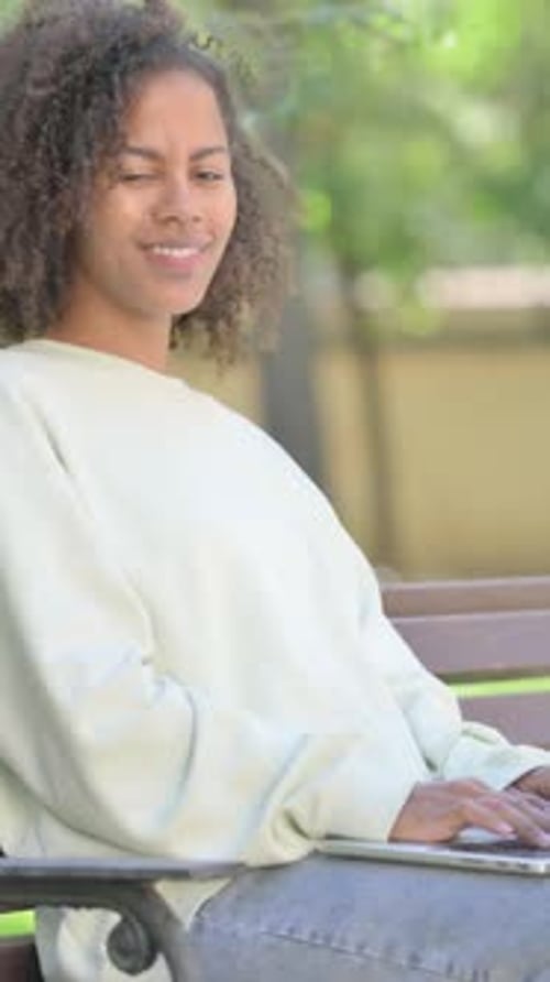 Young Woman Relaxing and Smiling on Park Bench