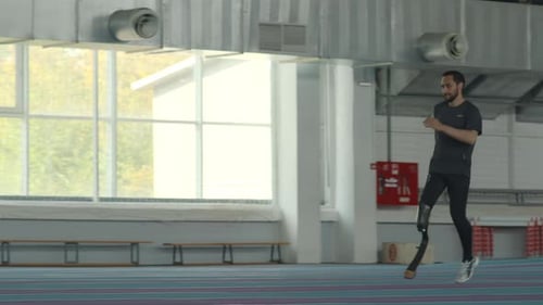 Man with Prosthetic Leg Running on Indoor Track