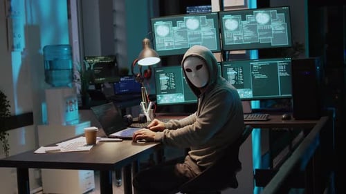 Un criminel porte un masque et une capuche pour pirater un système informatique