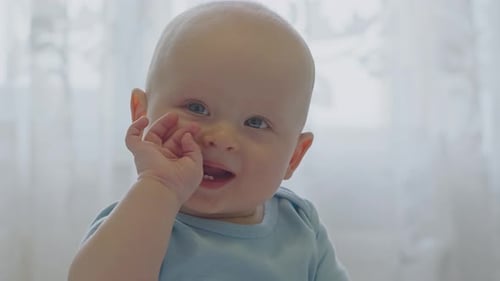 Cute Bald Baby Smiling and Chewing Fingers