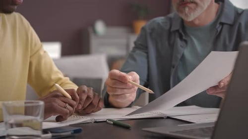 Two Adults Reviewing Budget Documents at Desk