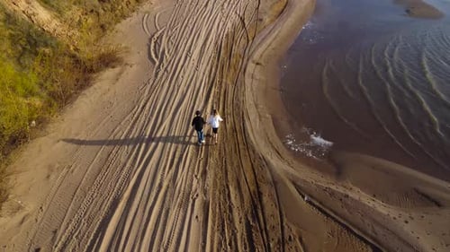 A Loving Couple Walking Hand in Hand on a Beautiful Sandy Beach During a Breathtaking Sunset