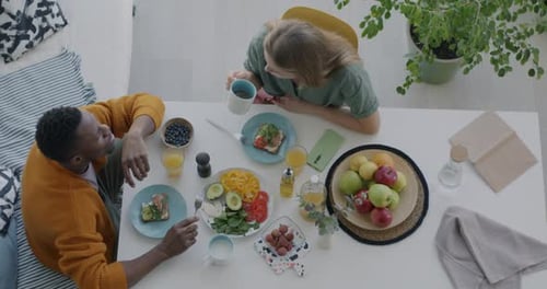 Top View of Man and Woman Happy Biracial Couple Talking and Eating Healthy Meal Having Lunch at Home