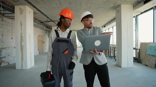 Architect Showing Instructions on Laptop to Construction Worker