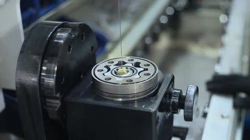 Factory worker lubricating industrial equipment with grease at metalworking plant