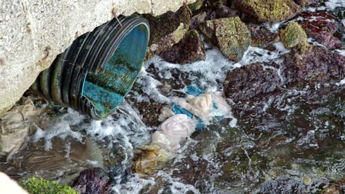 Schmutzwasser fließt aus dem Rohr der Fabrik in den schmutzigen Fluss mit Müll