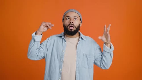 Young Adult Man Gesturing on Orange Background