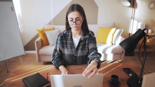 Girl in Home Office on Table at Place of Work Opens Laptop Screen and Starts Working