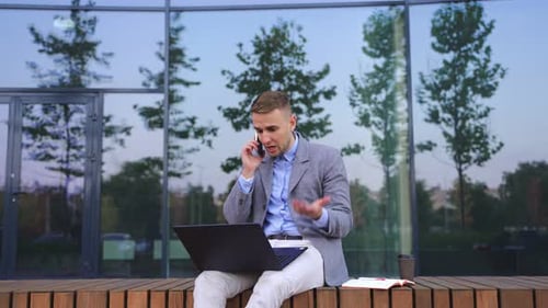 Young Adult Working On Laptop While Talking on Phone