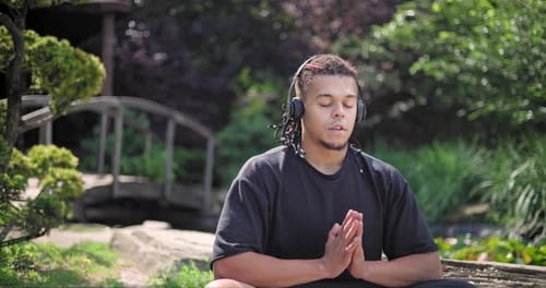 Young African American Spirituality Man Meditating Yoga Asana Sitting in a Park Outdoor and