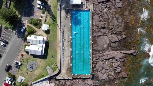 Top-Down Ascend of Shellharbour Ocean Pool With Rocky Coast and Breaking Waves