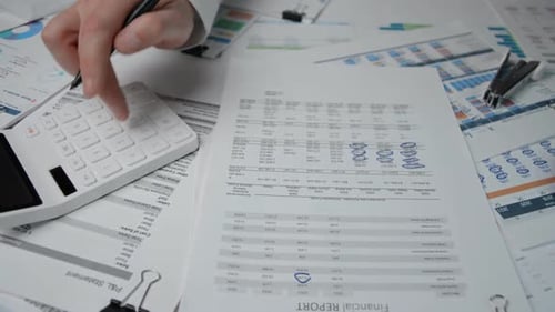 Reviewing Financial Report with Calculator and Pen
