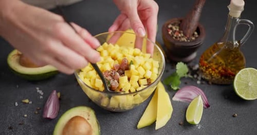 Woman Mixing Chopped Tuna Mango Cilantro and Onion in a Glass Bowl Cooking Traditional Tuna and